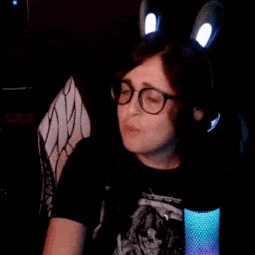 a woman wearing glasses and bunny ears is sitting in a dark room .