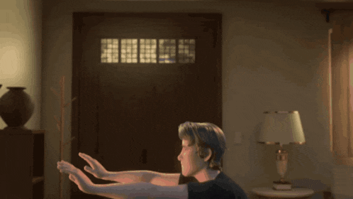 a man in a black shirt is standing in a room with a lamp