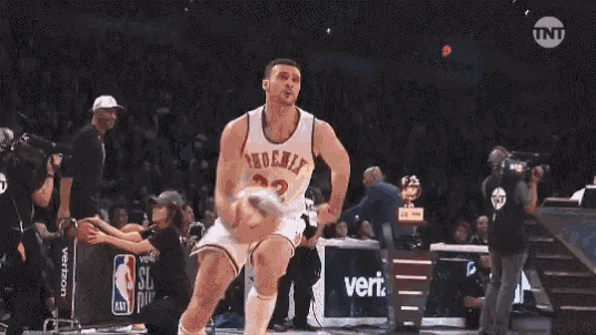 a basketball player is jumping in the air during a game with a state farm sign in the background .