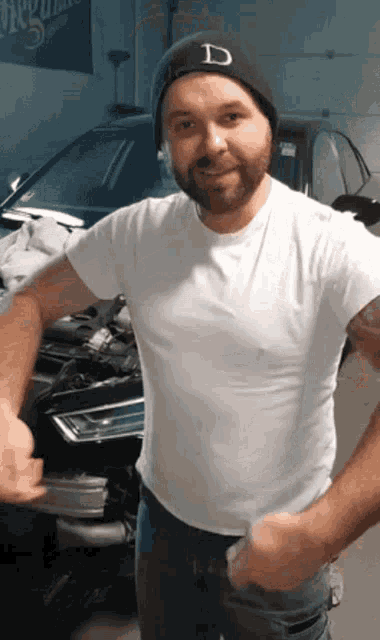 a man wearing a white shirt and a black beanie with the letter d on it