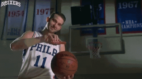 a man in a philadelphia jersey holds a basketball in his hands