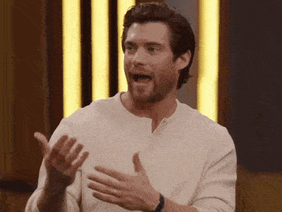 a man in a white shirt is making a funny face with his mouth open and his hands outstretched .