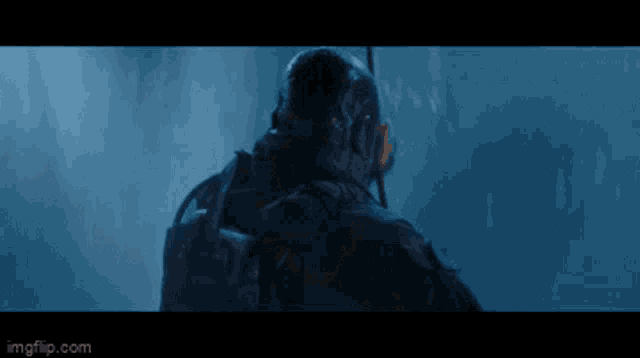 a man in a helmet is standing in front of a blue wall .