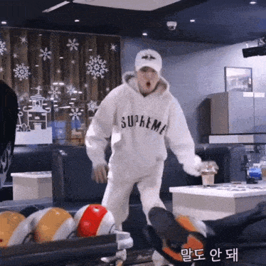a person wearing a white supreme hoodie is standing in front of a bowling alley