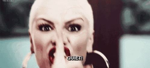 a close up of a woman 's face with a finger in her nose and the words quiet .