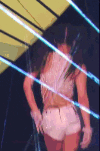 a woman in a white top and white shorts is dancing in a dark room
