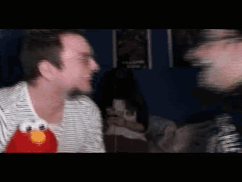 a man in a striped shirt has a stuffed elmo on his shirt