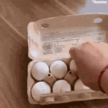 a person is opening a carton of eggs on a table .