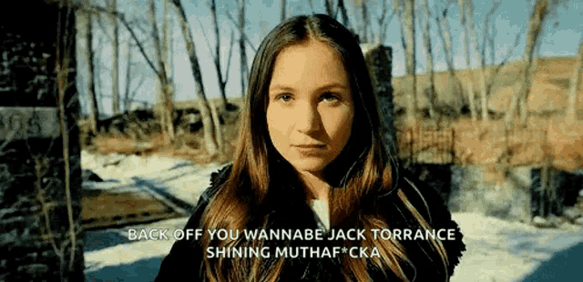 a girl with long hair is standing in front of trees and a sign that says back off you wannabe jack torrance