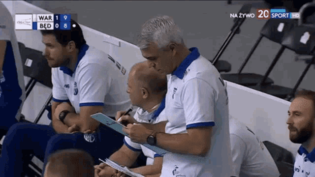 a group of men sitting in a stadium watching a game with a scoreboard that says war 1 bed 0