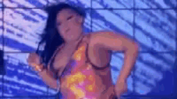 a woman in a pink and orange dress is dancing in front of a blue and white wall .