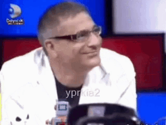a man wearing glasses is sitting in front of a television .