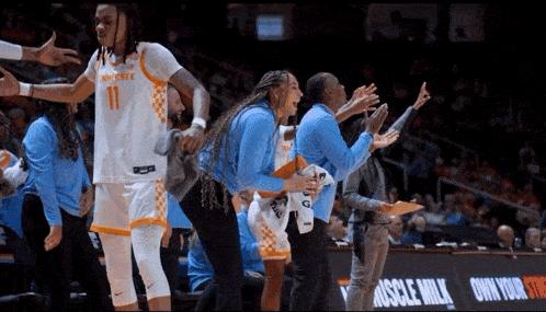a tennessee basketball player stands on the sidelines with her teammates