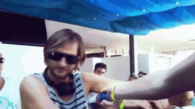a man wearing sunglasses and headphones is holding a woman 's arm