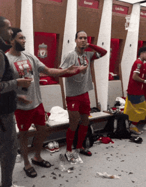 soccer players in a locker room with one wearing a shirt that says ' liverpool ' on it