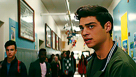a young man is standing in a hallway with a crowd of people behind him .