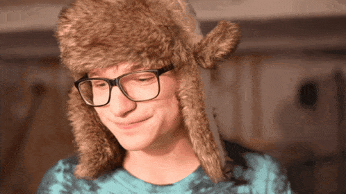 a young man wearing glasses and a furry hat
