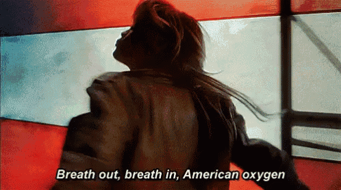 a woman is standing in front of an american flag and saying breath out breath in american oxygen