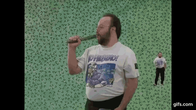 a man with a beard wearing a shirt that says no pregnancy is holding a stick .