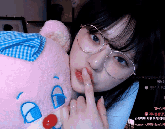 a woman wearing glasses is holding a stuffed animal