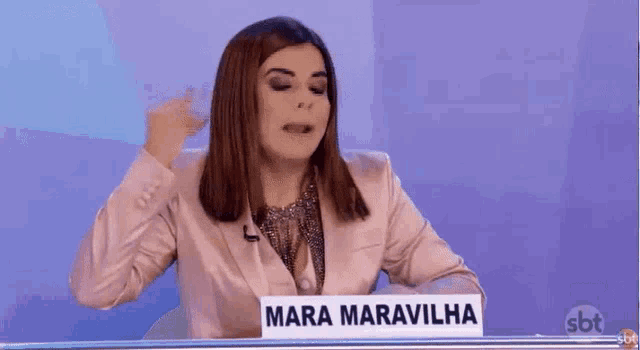 a woman is sitting at a table holding a sign that says mara maravilhosa
