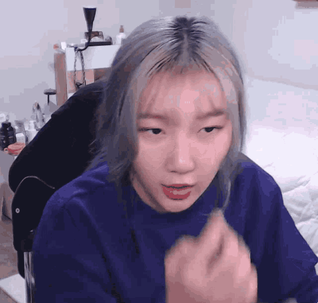 a girl with blonde hair is wearing a blue shirt and making a funny face