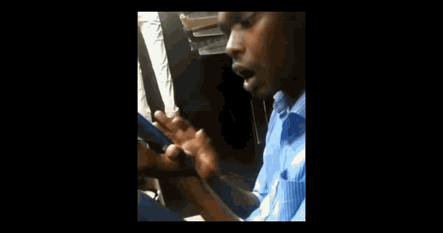 a man in a blue shirt is talking on a cellphone