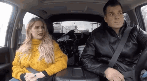 a man and a woman are sitting in the back of a car