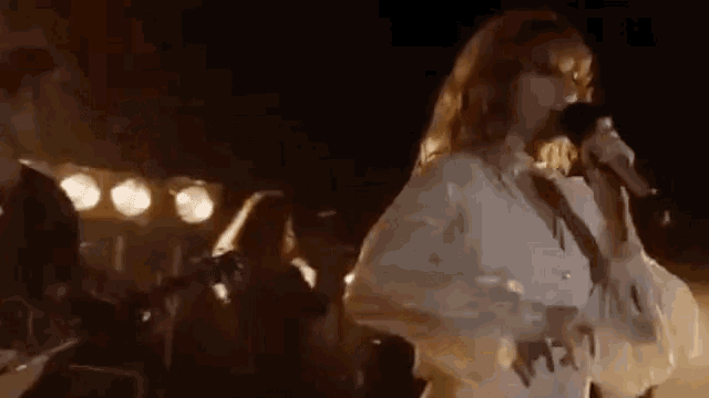 a woman is singing into a microphone while a man plays a guitar .