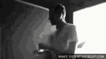 a black and white photo of a man standing in front of a window