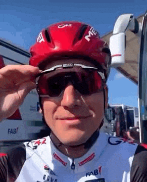 a man wearing a red helmet and sunglasses is taking a selfie .