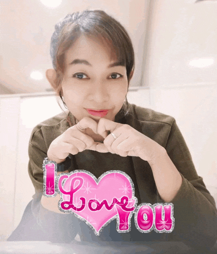 a woman is making a heart shape with her hands and the words i love you are behind her