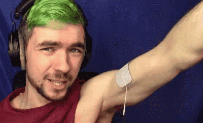 a man with green hair and headphones is flexing his muscles .