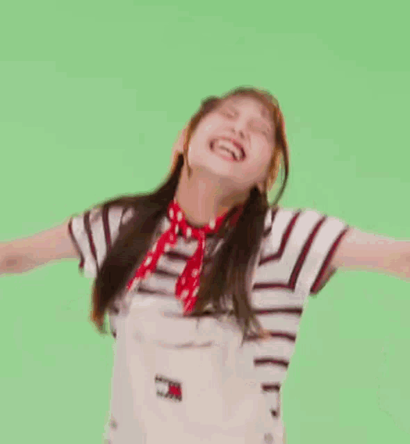 a woman is making a funny face in front of a green screen while dancing .