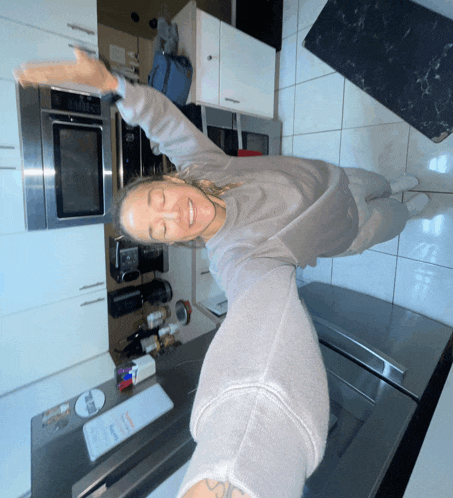 a woman taking a selfie in a kitchen with a sticker on the refrigerator that says ' ice '
