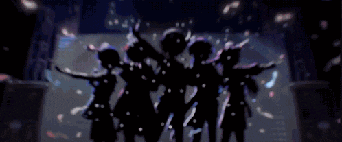 a group of girls are standing on a stage with their arms in the air