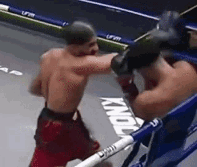 two men are boxing in a ring and one of them is wearing boxing gloves .