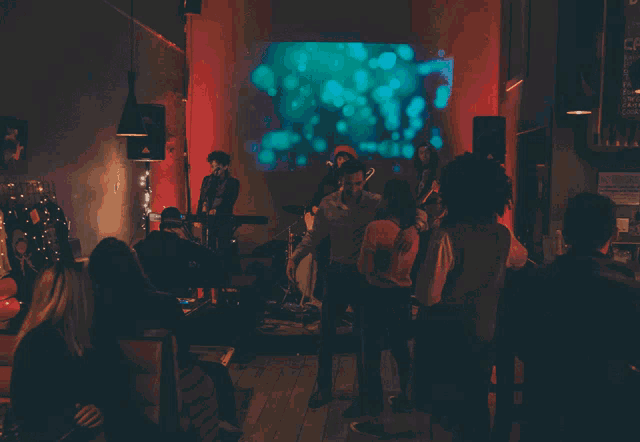 a group of people are dancing in a dark room with a sign on the wall that says no smoking
