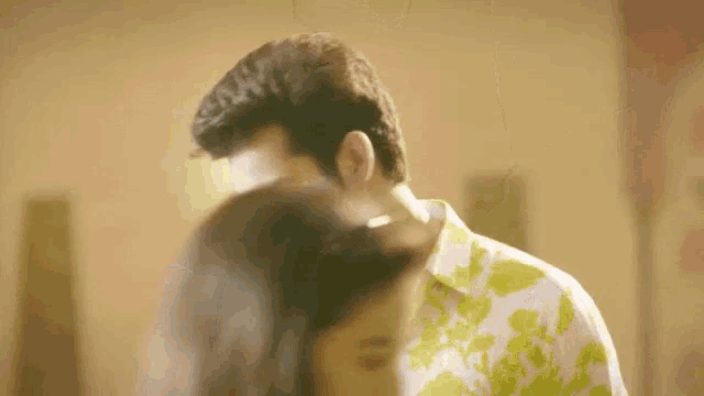 a man in a yellow and white shirt holds a woman 's hair