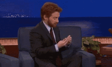 a man in a suit and tie is sitting in a chair with his legs crossed