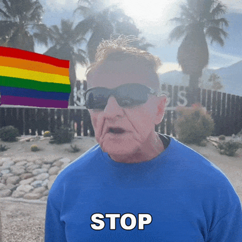 a man wearing sunglasses and a blue shirt with the word stop on it