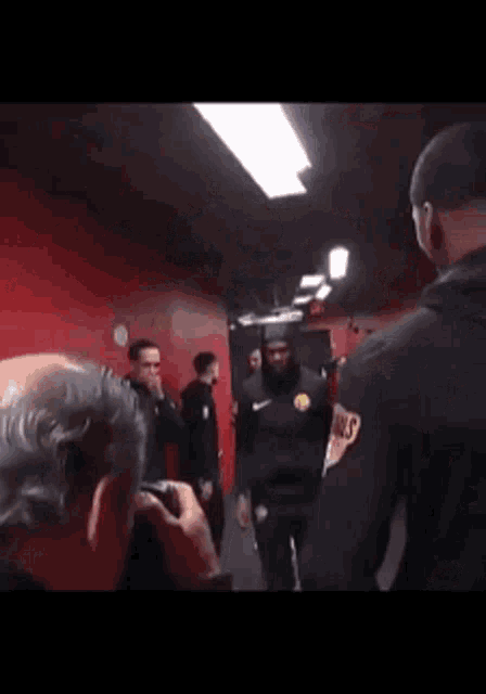 a group of people are standing in a room with red walls