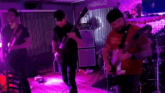 a man wearing a red shirt that says " great for nothing " plays a guitar