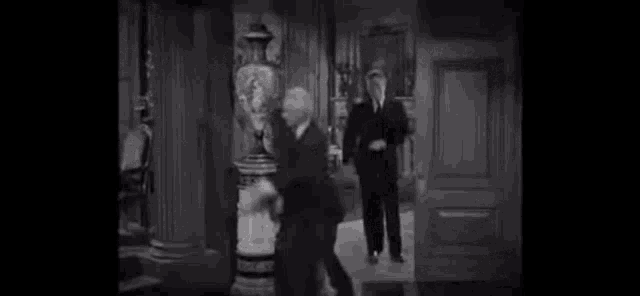 two men are fighting in a room in a black and white photo .