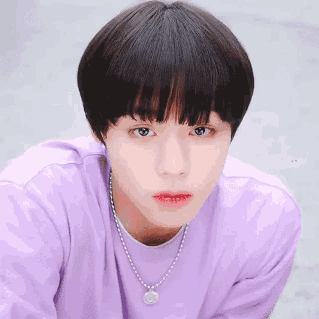 the boy is wearing a purple shirt and a necklace .