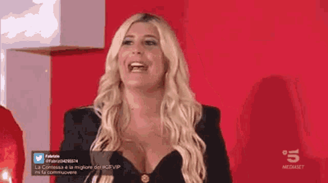 a woman is laughing in front of a red wall with the number 5 on the bottom right