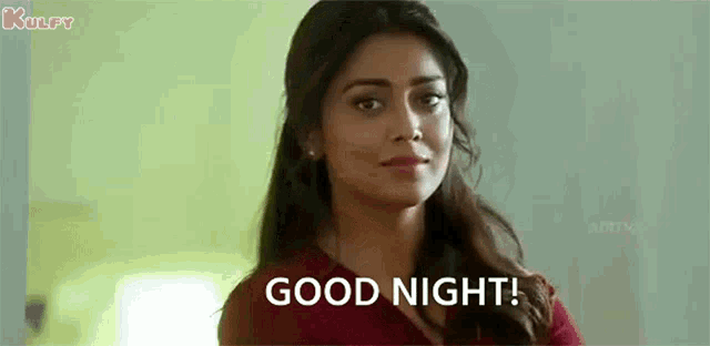 a woman is standing in front of a window and saying `` good night '' .