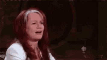 a woman with long red hair is crying while sitting in front of a piano .