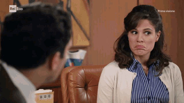 a woman is making a funny face while sitting in front of a man with rai hd in the corner