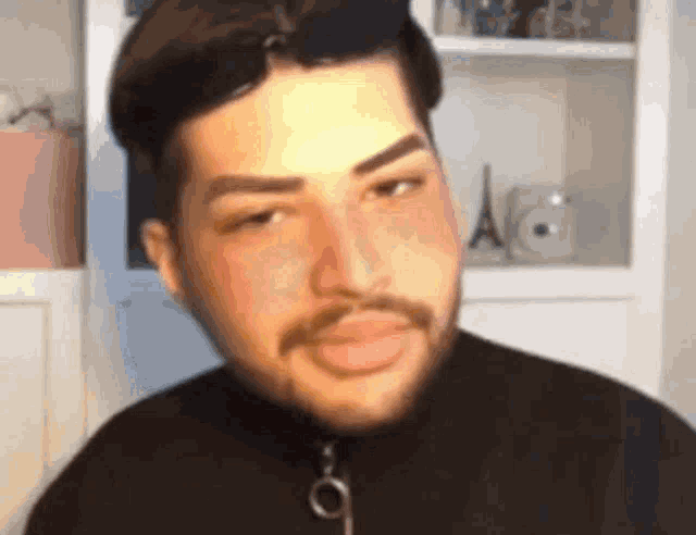 a man with a beard is making a funny face while wearing a black shirt .